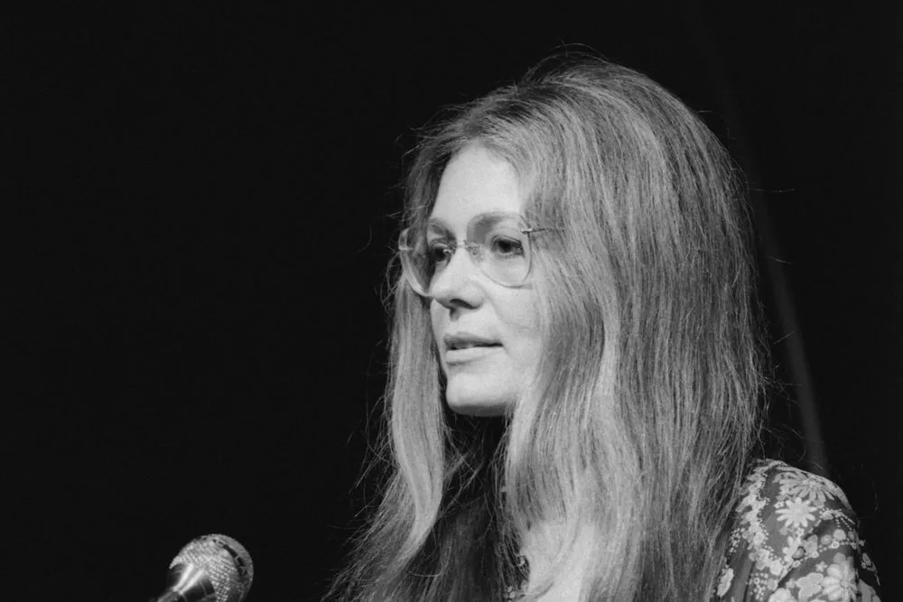 Gloria Steinem speaking at a microphone in 1975